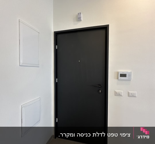 דלת שחורה עם ידית ומנעול על קיר לבן